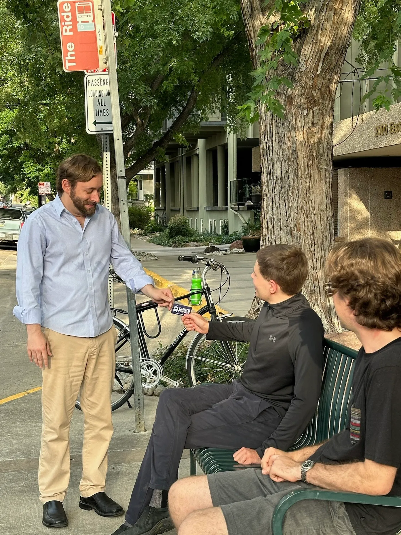 A photo of Christopher with a voter at a bus stop.